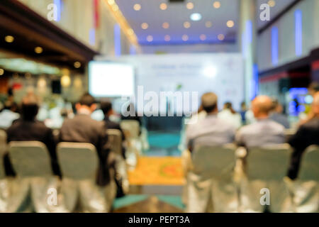 Vista offuscata da dietro il pubblico in attesa di sentire dall'altoparlante nel seminario in costruzione su sfondo sfocato. Foto Stock