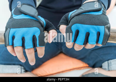 Maschio in mani guanti blu sul vecchio remi in legno, close-up Foto Stock