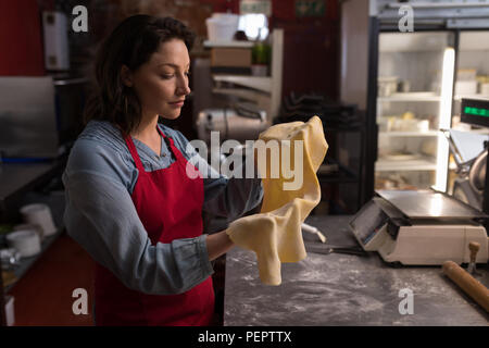 Il panettiere di sesso femminile in possesso di una pasta a mano Foto Stock