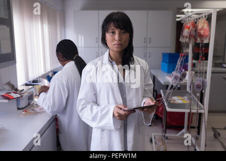 Tecnico di laboratorio utilizzando tavoletta digitale Foto Stock