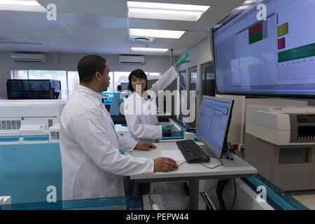 Tecnici di laboratorio a discutere su uno schermo di visualizzazione Foto Stock