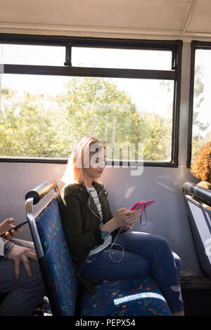 Donna ascoltare musica mentre si è in viaggio in bus moderno Foto Stock