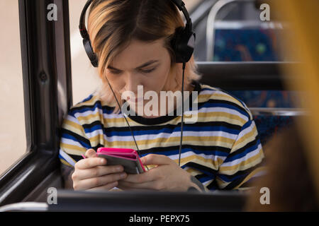 Donna ascoltare musica mentre si è in viaggio in bus moderno Foto Stock