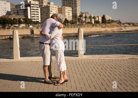 Coppia senior che abbraccia ogni altra vicino lato mare Foto Stock