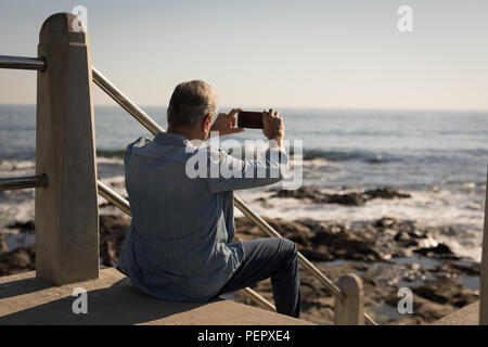 Uomo senior di scattare le foto dal telefono cellulare Foto Stock