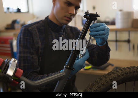 Uomo che ripara sellino per bicicletta in officina Foto Stock