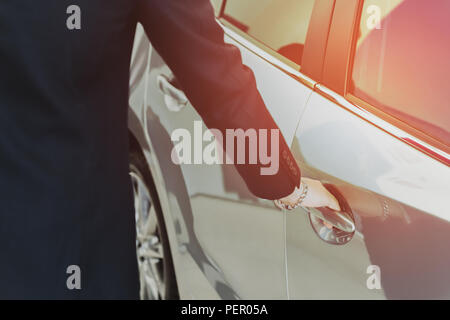 Salemans mano sulla maniglia per l'apertura di una portiera della macchina con la luce del sole in matte. Foto Stock