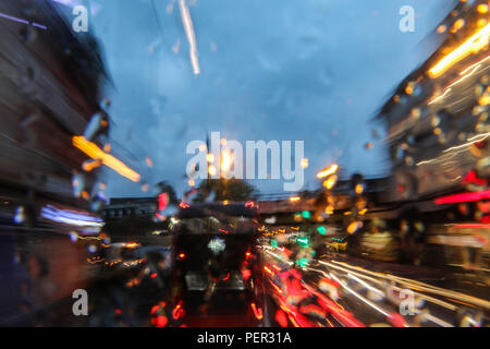 Una foto dal bus di pilotaggio in serata città durante la pioggia. Tutto è sfocato astrattamente in tracce di colori. Foto Stock