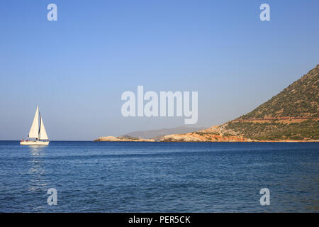 White in barca a vela in mare aperto. Sailing yacht in mare aperto con le montagne sullo sfondo. Foto Stock