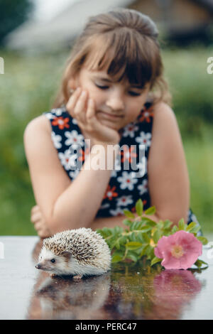 Bambina e la pungente riccio in estate a tavola Foto Stock