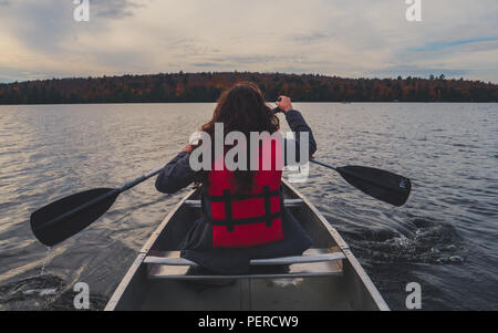 Due ragazze canoa con argento canoa sul lago in Canada algonquin national park in una soleggiata giornata nuvolosa durante la caduta Foto Stock