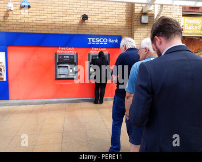 Le persone in attesa in una coda per utilizzare quello rimanente ATM di lavoro presso il supermercato Tesco a Rotherham, South Yorkshire, Inghilterra Foto Stock