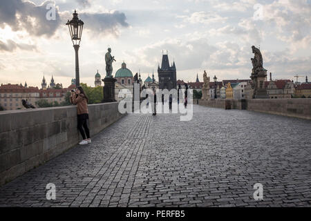 Visitatori camminando sul Ponte Carlo, uno storico ponte che attraversa il fiume Vitava a Praga, all'alba, Repubblica Ceca. Foto Stock