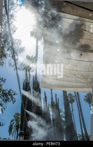 Tenda gli sprinkler e gli spruzzi di acqua nebulizzata a parco pubblico. Dispositivi per il raffreddamento della calda estate la temperatura in Spagna all'aperto Foto Stock