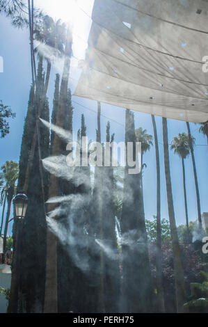 Tenda gli sprinkler e gli spruzzi di acqua nebulizzata a parco pubblico. Dispositivi per il raffreddamento della calda estate la temperatura in Spagna all'aperto Foto Stock