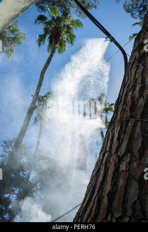 Tenda gli sprinkler e gli spruzzi di acqua nebulizzata a parco pubblico. Dispositivi per il raffreddamento della calda estate la temperatura in Spagna all'aperto Foto Stock