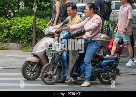 Suzhou, Jiangsu, Cina. Il cinese con moto elettrico. Foto Stock