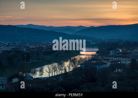 Il sole sorge lungo il fiume Arno e la periferia di Firenze, con le colline Fiesolean fornendo uno sfondo. Foto Stock