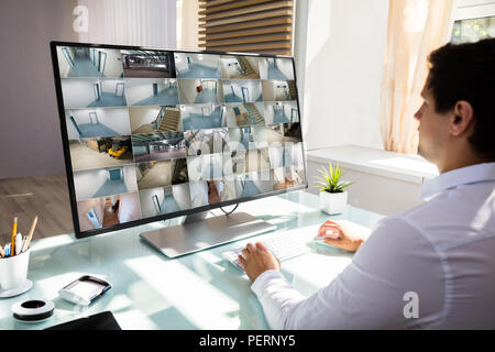 Giovane imprenditore controllo telecamera TVCC filmati sul computer sulla scrivania in ufficio Foto Stock