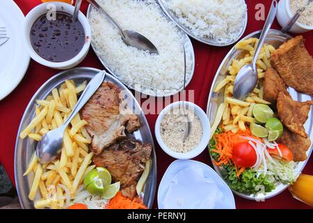 Cucina brasiliana - grigliate di carne e pesce con fagioli neri, patatine, farofa e riso. Foto Stock