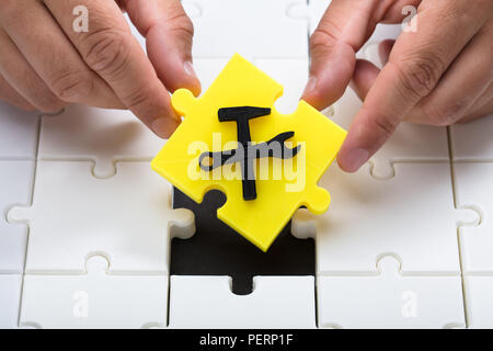 Mano umana ponendo ultimo pezzo giallo con in costruzione icona in puzzle Foto Stock