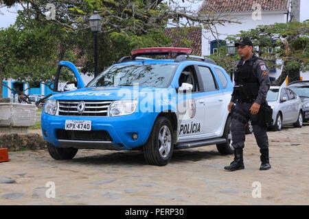 PARATY, Brasile - 14 ottobre 2014: funzionario di polizia cammina accanto a Renault Duster auto della polizia a Paraty (nello stato di Rio de Janeiro). PMERJ polizia di stato empl Foto Stock