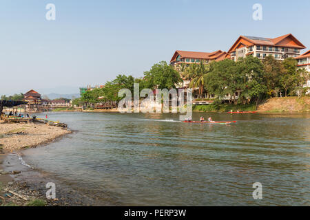 Poche persone e barche sul Nam Song River e alberghi in Vang Vieng, Provincia di Vientiane, Laos, in una giornata di sole. Foto Stock