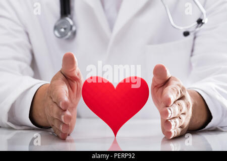 Medico di protezione mano cuore rosso sulla scrivania Foto Stock