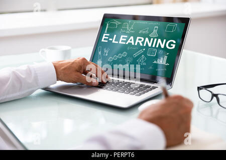 Close-up di un imprenditore il lato con il computer portatile che mostra l'E-learning concetto sullo schermo Foto Stock