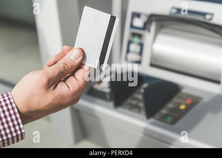 Close up man mano azienda carta di credito accanto all'atm. Foto Stock