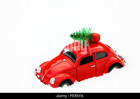 Giocattolo rossa scarabeo di Volkswagen auto con un albero di natale legata al tetto su un inverni nevosi giorno concetto di Natale Foto Stock