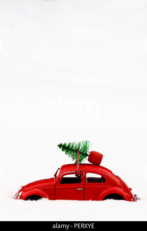 Giocattolo rossa scarabeo di Volkswagen auto con un albero di natale legata al tetto su un inverni nevosi giorno concetto di Natale Foto Stock