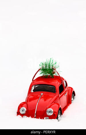 Giocattolo rossa scarabeo di Volkswagen auto con un albero di natale legata al tetto su un inverni nevosi giorno concetto di Natale Foto Stock