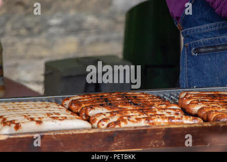 Tedesco barbecue salsicce alla griglia essendo da un fornitore nel mercato di Borough, Southwark, Londra UK Foto Stock