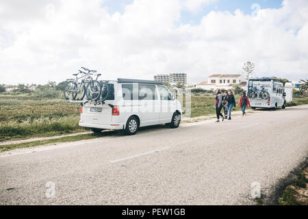 Il Portogallo, Lagos, 12 Aprile 2018: automobili per viaggiare con le biciclette parcheggiate a lato della strada. Le persone nelle vicinanze a piedi. Il riposo attivo e viaggi in famiglia. Foto Stock