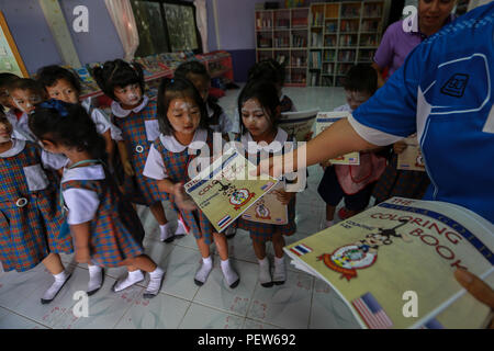 Piyawan Klaimonghol, insegnante di inglese presso il divieto Phrom scuola Nimit passa fuori libri da colorare per bambini in Wang Yeng Nam, Thailandia, durante l'esercizio Cobra Gold, 1 febbraio 2016. Cobra Gold 2016, nella sua trentacinquesima iterazione, include una specifica attenzione su umanitaria azione civica, impegno nella comunità, medici e le attività svolte durante l'esercizio per supportare le esigenze e gli interessi umanitari delle popolazioni civili attorno alla regione. (U.S. Marine Corps combattere la fotocamera dal Lance Cpl. Miguel A. Rosales/rilasciato) Foto Stock