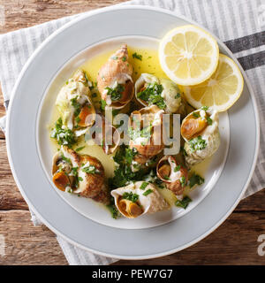 Ricetta francese conchiglia con una salsa di burro, aglio e prezzemolo, limone vicino sul tavolo. vista in pianta da sopra Foto Stock