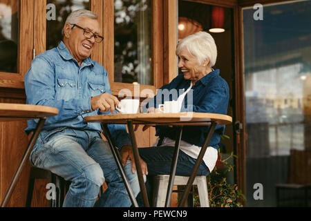 Coppia senior avente la conversazione mentre si beve il caffè insieme al cafe'. Sorridente ritirato l uomo e la donna seduta al tavolo del bar a parlare e avente il caffè Foto Stock