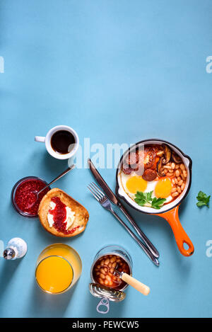 Prima colazione inglese nel recipiente di cottura con uova fritte, salsicce, fagioli, pane tostato e caffè sul tavolo in cemento, spazio di copia Foto Stock