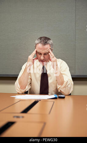 Un imprenditore caucasico seduti ad una scrivania che mostra lo stress del lavoro. Foto Stock