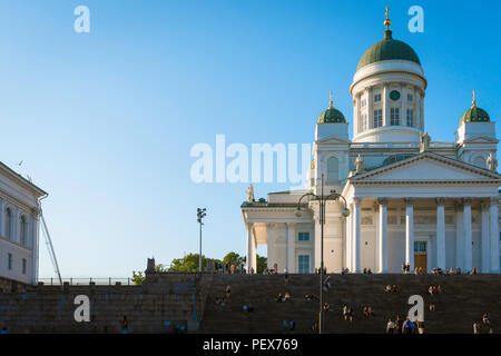 Finlandia il turismo estivo, vista al tramonto della cattedrale luterana di Helsinki con i turisti seduti su o salendo la scalinata per il suo ingresso. Foto Stock