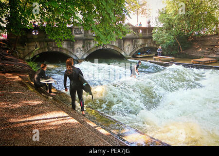 Monaco di Baviera, Germania - 24 luglio 2018 - Monaco di Baviera, surfisti in muta di pratica su onde artificiali sul Eisbach, piccolo fiume attraverso l'Englischer G Foto Stock