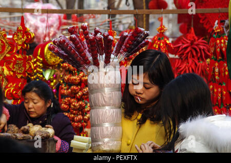 I fornitori stanno vendendo Sugarcoated Haws su un bastone e nodo cinesi nel mercato Foto Stock