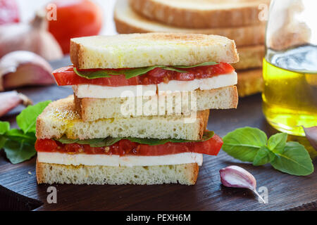 Sandwich con mozzarella, pomodoro, basilico, aglio e olio di oliva. Antipasto di delicatezza. Messa a fuoco selettiva Foto Stock