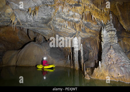 Un uomo ad esplorare il Krizna Jama grotta in barca. Regione carsica, Slovenia. Foto Stock