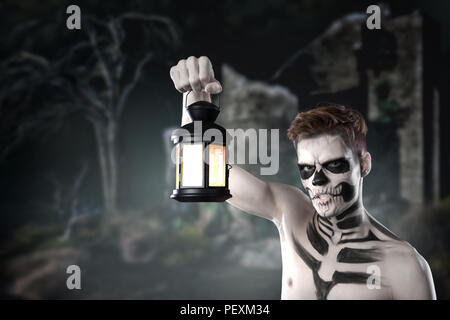 Il dia de los Muerto Costume - il giorno dei morti è una vacanza messicana. Qui è un uomo con il cranio faccia contro lo sfondo di una foresta di paura Foto Stock