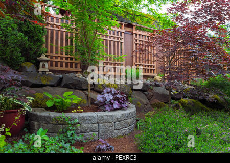 Home giardino nel cortile con il paesaggio naturale e pietra sovrapposti piantatrice pentole lanterna trellis alberi arbusti piante Foto Stock