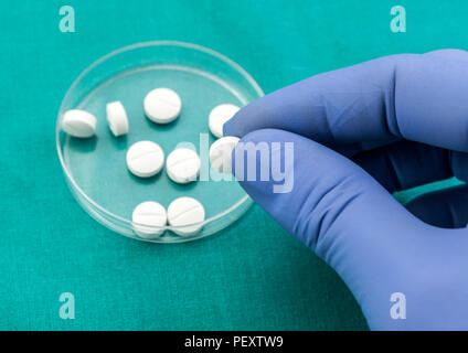 Medico sostiene nella sua mano alcune pillole di bianco Foto Stock