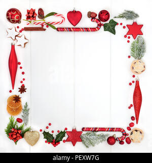 Abstract di Natale corona quadrata con una selezione di tradizionali simboli inclusi cibo, flora e albero ninnolo decorazioni su legno bianco sullo sfondo. T Foto Stock