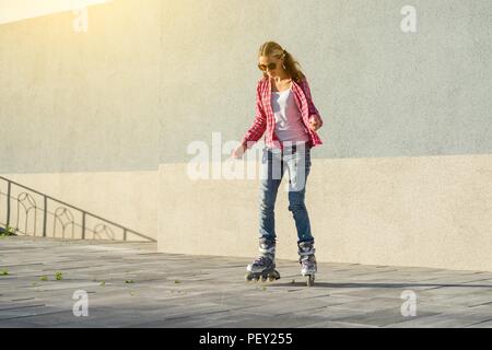 Active sport girl teen in pattini a rotelle sul background urbano Foto Stock